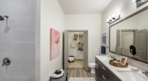 bathroom with hardwood floors and a painting on the wall and a door opening to a closet